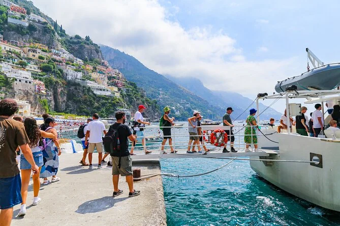 Visitors on the pier at Positano with boats and the cliffs behind